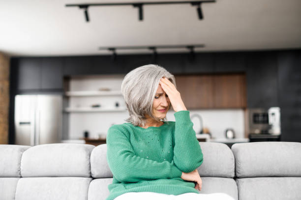 mujer anciana con migraña sentada en un sillon